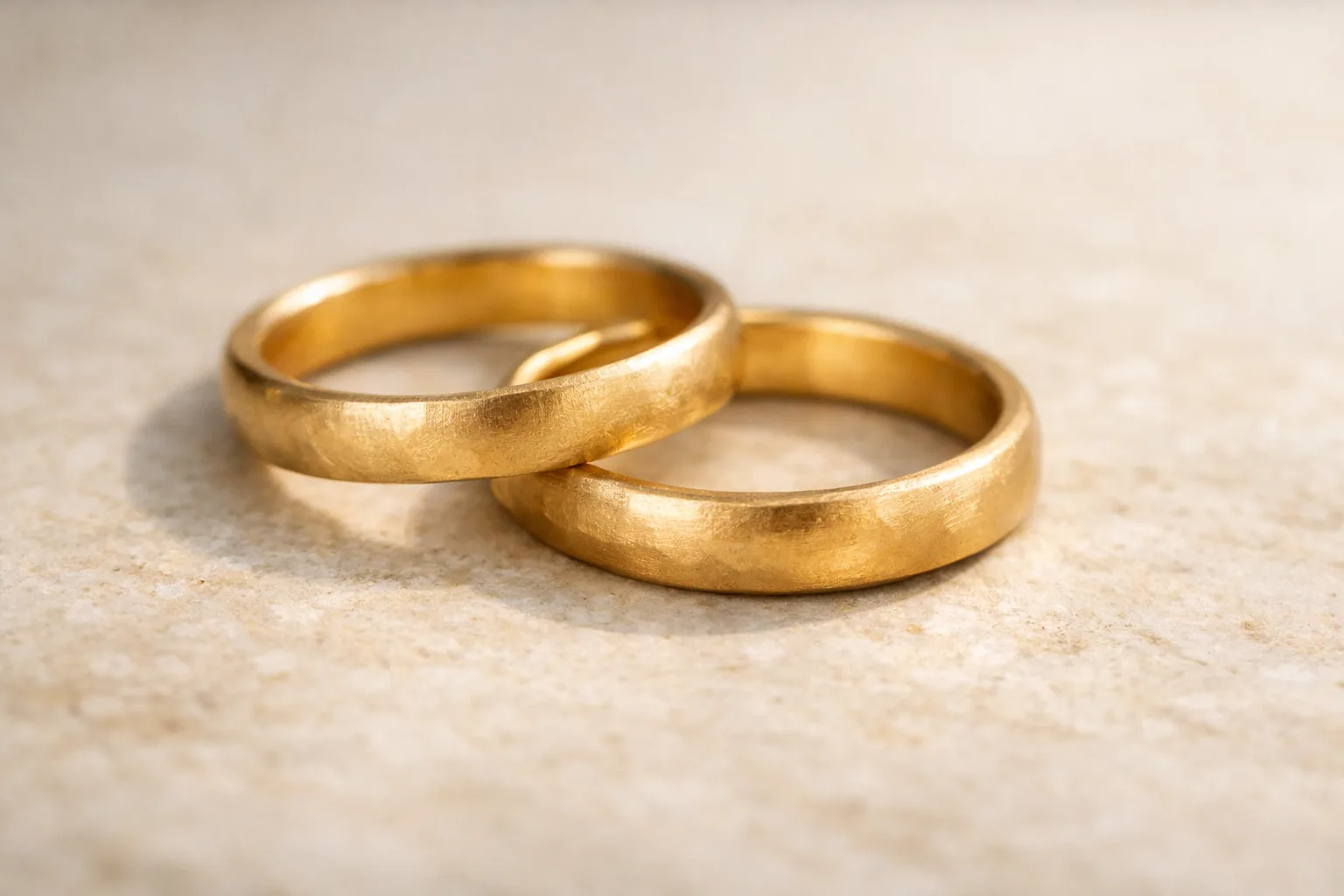 Coppia di fedi nuziali artigianali in oro posate su pietra naturale