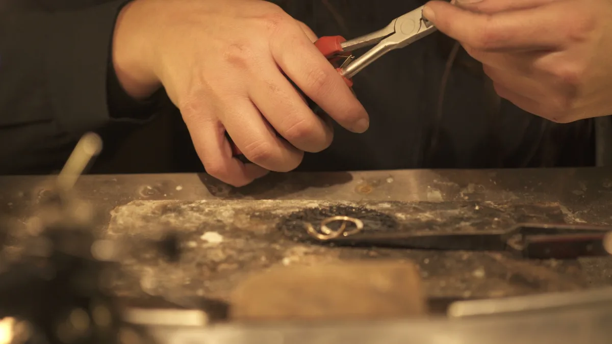 Dettaglio di mani che lavorano un gioiello con strumenti tradizionali