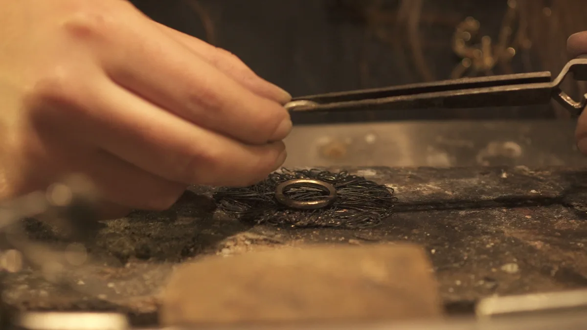 Dettaglio delle mani di Silvia che lucidano un gioiello appena forgiato